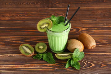 Glass of fresh kiwi smoothie with mint on wooden background