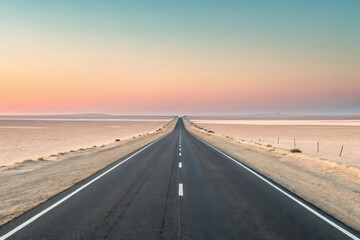 Naklejka premium Endless asphalt road through desert at sunrise