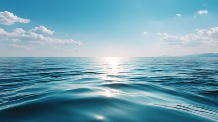 Fototapeta premium Serene ocean view with gentle waves reflecting sunlight under a clear blue sky and scattered clouds.