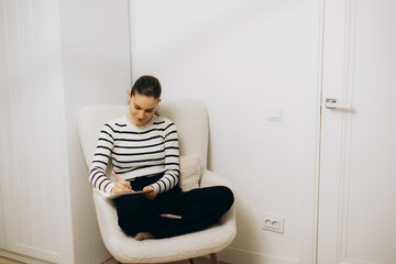 Woman Sitting Comfortably in Chair Writing in Notebook
