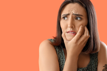 Beautiful young afraid woman on orange background