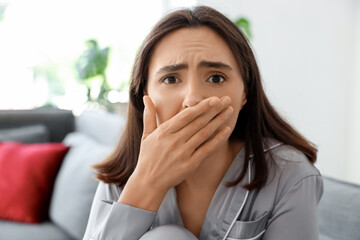 Beautiful young afraid woman in living room at home