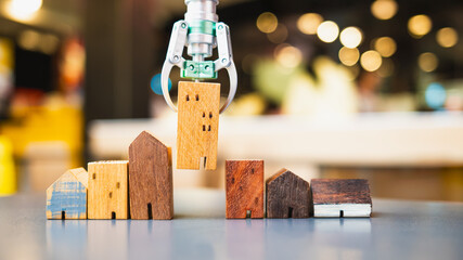 AI in real estate: A robotic arm lifts a tiny wooden house, showcasing technology's power to match homes with budgets and desired types.