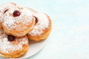 Plate with with tasty donuts for Hanukkah celebration on light background