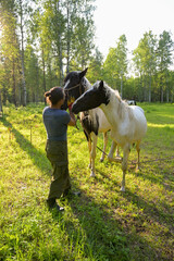rustic man with  horse in rural village near  forest.  horse farm is surrounded by nature, hay is stacked nearby,  peaceful and traditional.  man is caring for  horse