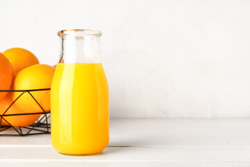 Bottle of fresh orange juice on white wooden table