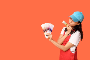 Female Asian painter with paint color palettes and brush on orange background