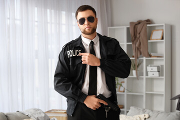 Male police officer with gun pointing at uniform indoors