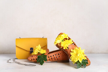 Stylish shoes with yellow bag and chrysanthemum flowers on white background