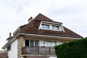 Two-Story House with Balcony, Red Tile Roof, and Bushes