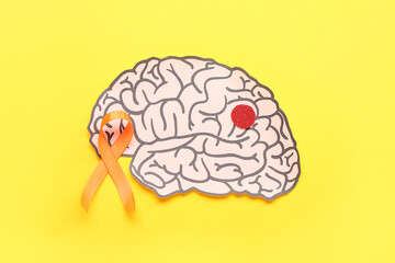 Paper brain and orange ribbon on yellow background. Multiple Sclerosis Awareness Month