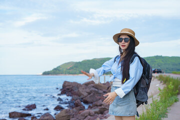 Female traveler enjoying the coastal view while wearing sunglasses and a hat near the ocean on a...