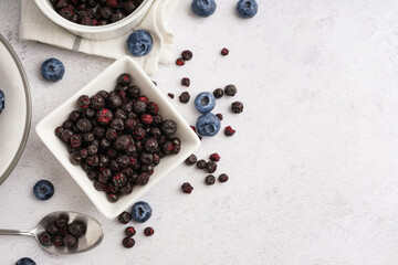 Bowl and spoon with freeze-dried blueberries on white background