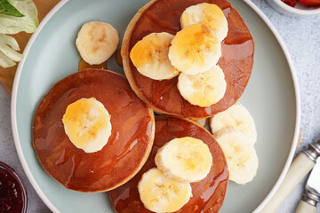 Stack of tasty pancakes with honey and banana on white background