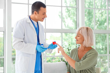 Obraz premium Male endocrinologist showing thyroid gland model to mature woman in clinic