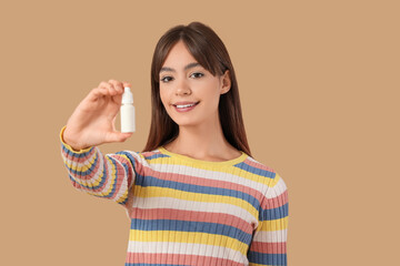 Young girl with eye drops on beige background