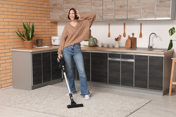 Beautiful young woman cleaning floor with modern vacuum cleaner while listening to music at home