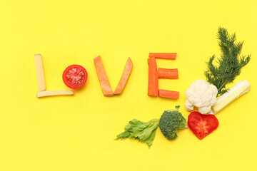 Composition with word LOVE and fresh vegetables on yellow background