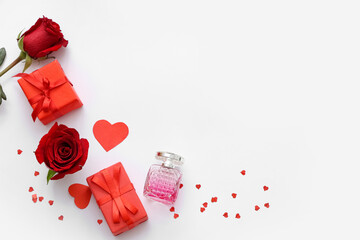 Bottle of perfume with beautiful red roses and gift boxes on white background. Valentine's day...
