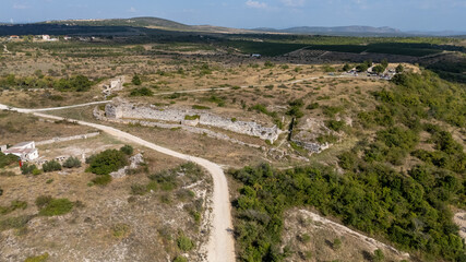 Aerial View of Ancient Ruins of Asseria, Croatia and Dirt Road in Hilly Landscape