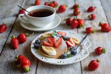 Light breakfast, pancakes with fruits and berries on the table.