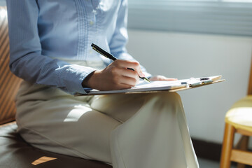 Businesswoman writing notes on clipboard during business meeting