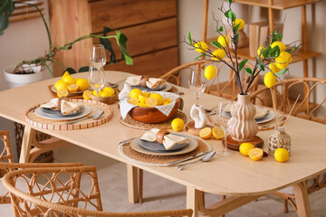 Stylish table setting decorated with many fresh citruses and beautiful lemon tree branches in...