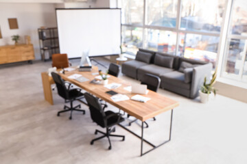 Blurred view of conference hall with table, sofa and projector screen