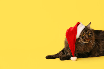 Cute cat in Santa hat on yellow background