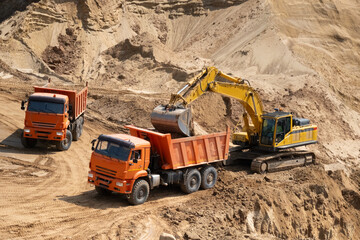 The process of loading sand in a sand quarry. Trucks are waiting for cargo.