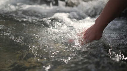 A woman's hand plays with fresh clean water from the river.