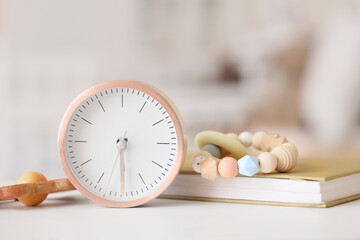 Alarm clock, book and toys on table in children's room, closeup