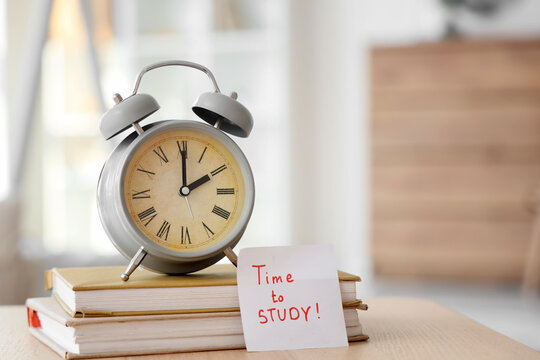 Alarm clock, books and sticky note with text TIME TO STUDY on table in children's room, closeup