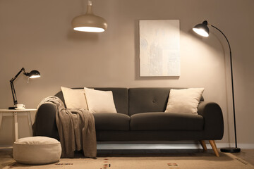 Comfortable sofa and glowing lamps in interior of modern living room