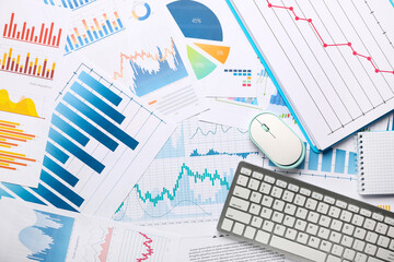 Keyboard with computer mouse, many business graphics and diagrams as background, closeup