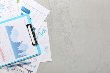 Clipboard with pen, business graphics and diagrams on grunge grey background