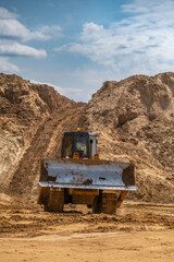 A crawler tractor with a bucket works in a sand quarry.