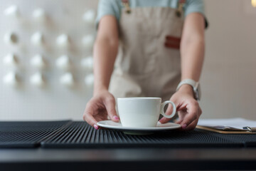 Barista serving espresso coffee in cafe, placing cup on counter