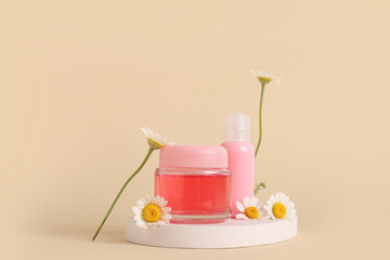 Plaster stand, bottle and jar of cosmetic products with chamomile flowers on beige background
