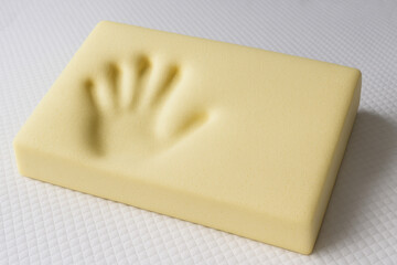 Memory Foam Pillow: An up-close shot of a soft, yellow memory foam pillow imprinted with the impression of a hand, hinting at comfort and personalized support.