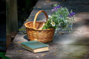 A basket of wild flowers on a wooden bridge on a sunny summer day.