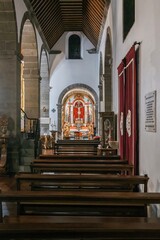 Inside a historic Portuguese church, featuring chandeliers hanging from the high ceiling, leading...