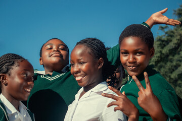Real photo of cheerful African kids in school uniforms, enjoying time together outdoors. A natural moment full of smiles, youth, friendship, and positive energy. 
