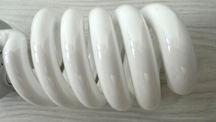 Close up of large spiral compact fluorescent light bulbs (CFL). Energy-saving daylight lamps with E27 screw base on light wooden background, top view