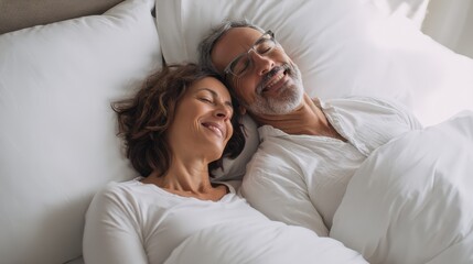 A mature couple lies peacefully in bed, smiling and enjoying a relaxed moment together.