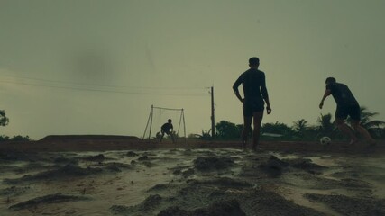 Football players taking shots at a goalpost in the rain, slow motion shot