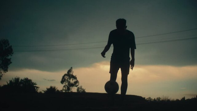 Dribbling the football, slow motion, silhouette of player in dramatic lighting
