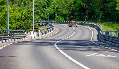 A car is driving down a road with a yellow line on the side
