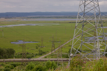 Electricity pylons on the background of the river in summer