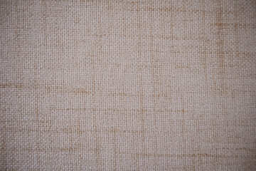 Close-up of fabric texture with detailed woven fibers in natural beige tones. Rustic material and eco-friendly textile